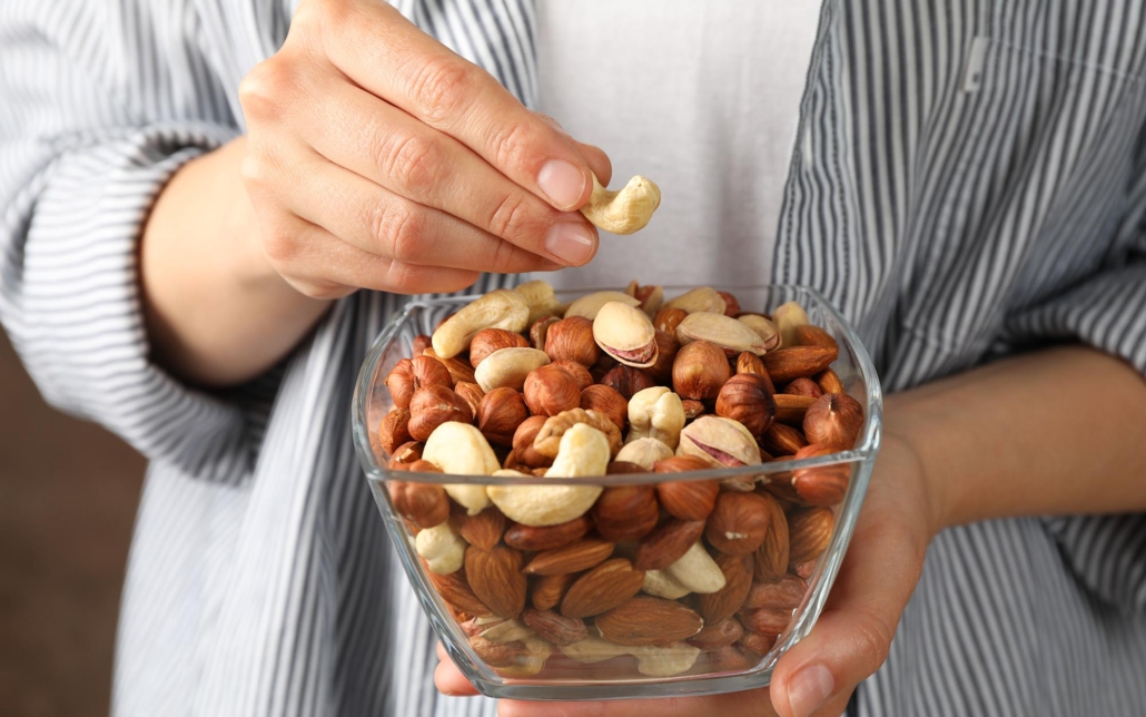 Front view of a man in a striped shirt eating nuts out of a bowl