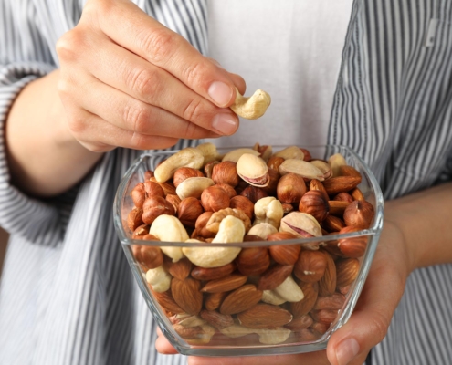 Front view of a man in a striped shirt eating nuts out of a bowl