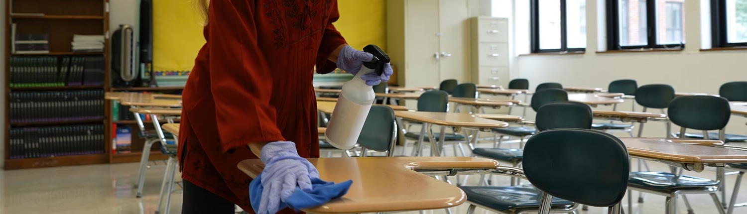 Side view of a woman cleaning up school desks